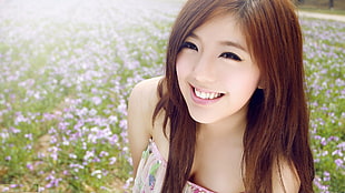 woman in pink and green floral strapless top taking picture with field of purple-and-white petaled flower field smiling during daytime HD wallpaper